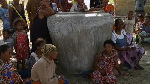 A group of women sit next to a giant concrete jar at a launch event